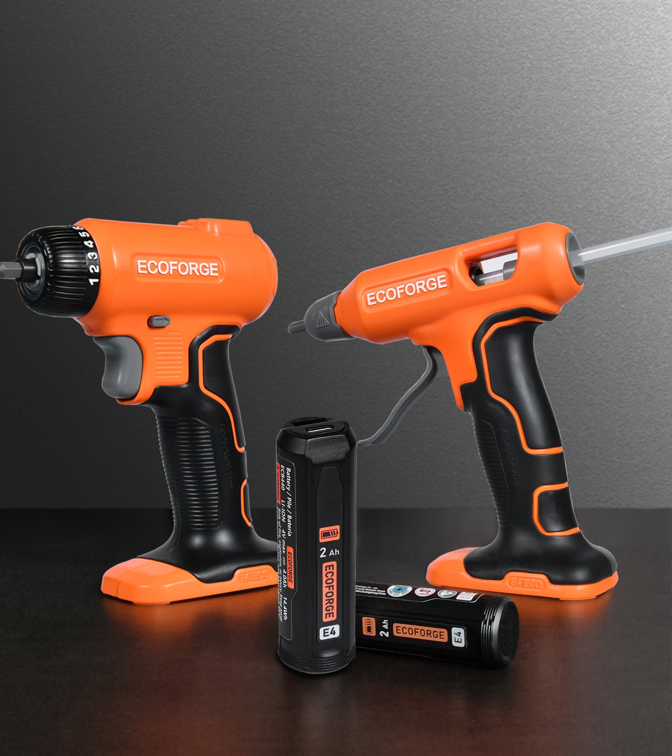 Two orange and black Ecoforge cordless power tools on a dark surface against a gray background, with two black batteries in front.